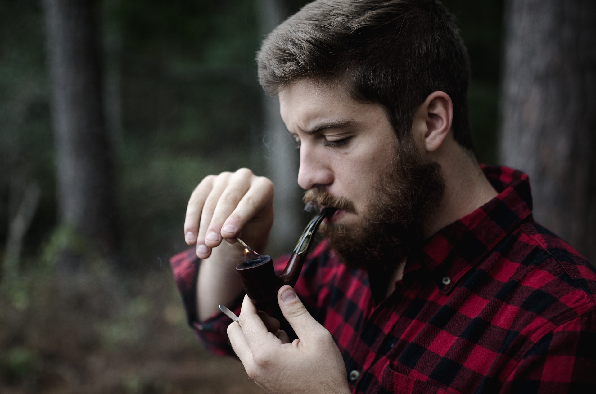 Man outdoors lighting a smoking pipe