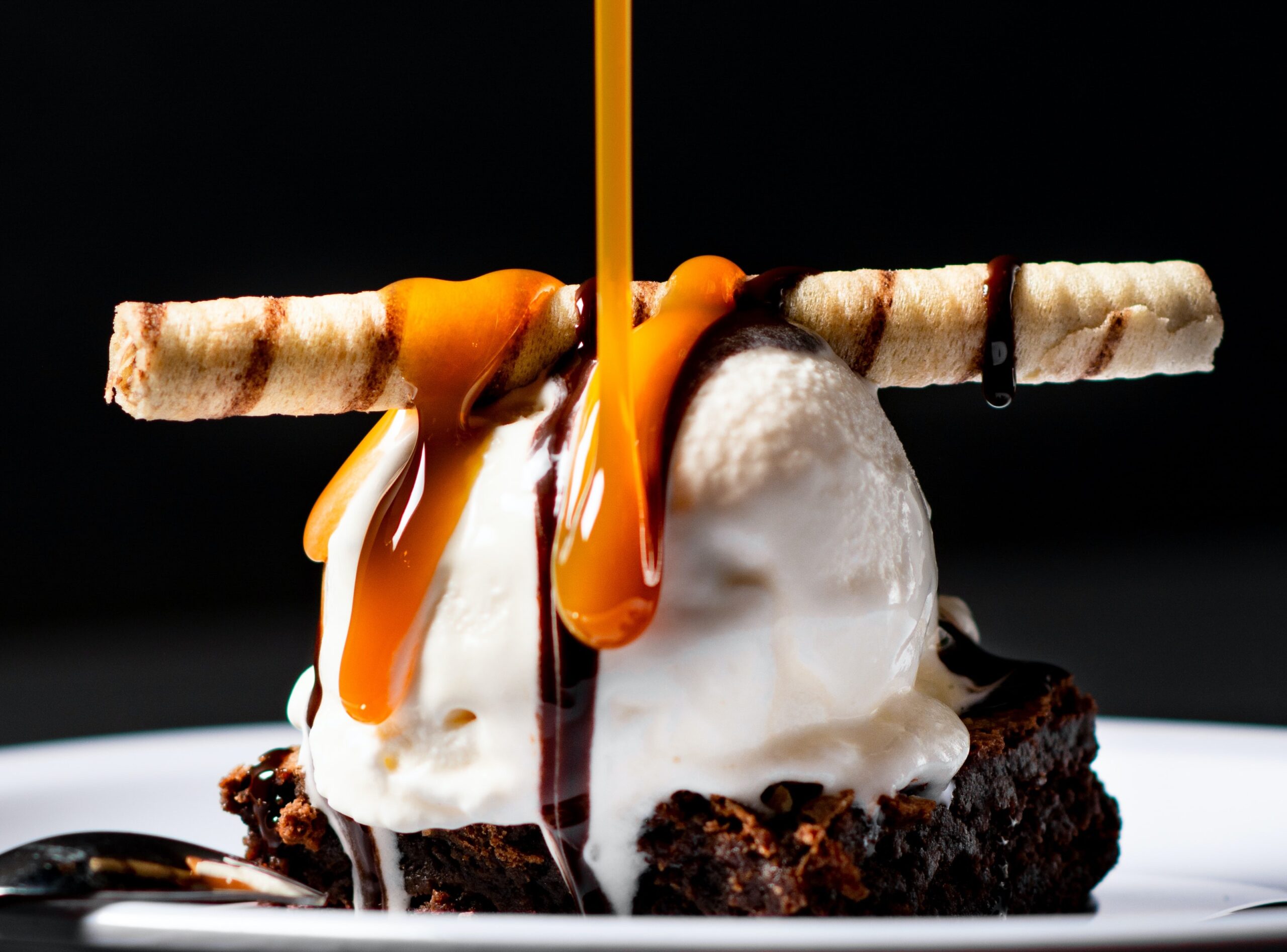 A chocolate brownie with ice cream and a wafer cigar